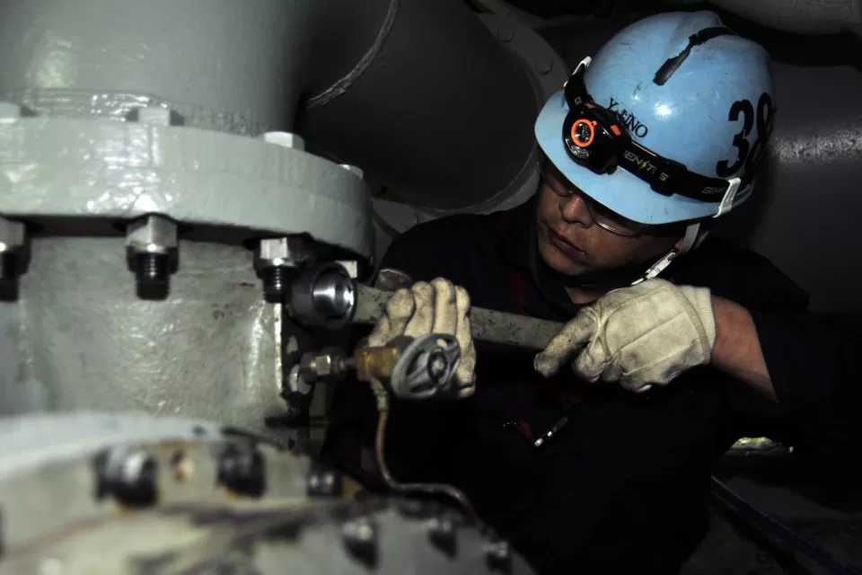 Japanese shipyard worker performs preservation work on ships air conditioning system.
